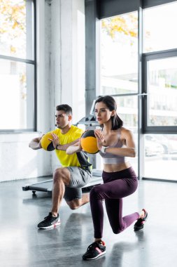 Sporcu ve sporcu kadın spor merkezinde toplarla hamle yapıyor.