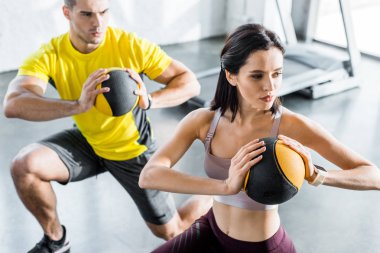 Sporcu ve sporcu kadın spor merkezinde toplarla hamle yapıyor.