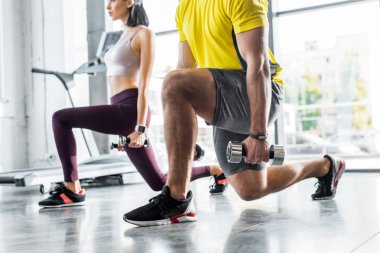 Sporcu ve sporcunun spor merkezinde dambıllarla hamleler yaptığı görüntüler.