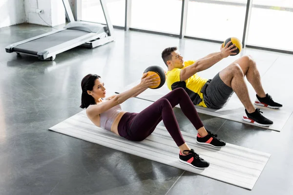 在体育中心 运动员和女运动员拿着健身垫上的球在操练 — 图库照片