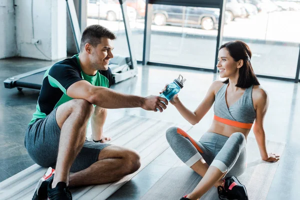 Glimlachende Sportman Geeft Sportfles Aan Sportvrouw Sportcentrum — Stockfoto