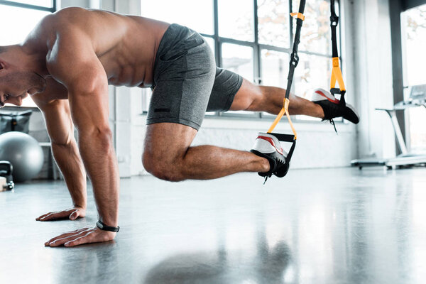 handsome sportsman working out on suspension trainer in sports center 