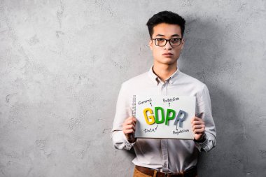 asian businessman holding paper with gdpr lettering and looking at camera  clipart