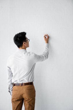 beyaz duvara yazı yazan seo yöneticisinin arka görünümü 