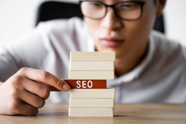Asyalı seo yöneticisinin seçici odak noktası harf seosuyla ahşap dikdörtgen tutması 