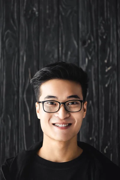 Sonriente Asiático Hombre Gafas Mirando Cámara Madera Fondo — Foto de Stock