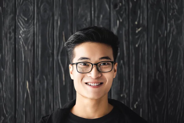 Sonriente Asiático Hombre Gafas Mirando Cámara Madera Fondo — Foto de Stock