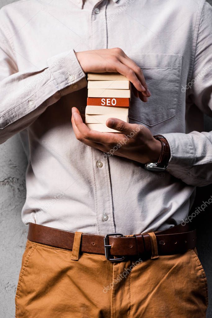 cropped view of seo manager holding wooden rectangles with lettering seo 