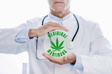 Beyaz önlüklü doktorun tıbbi marihuana resimlerinin yanında el ele tutuşması.