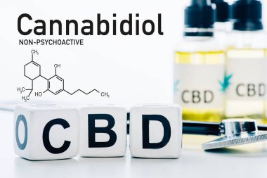Yağ ve steteskop yanında cbd harfleri olan küplerin seçici odak noktası cbd moleküllü beyaza izole edilmiş.