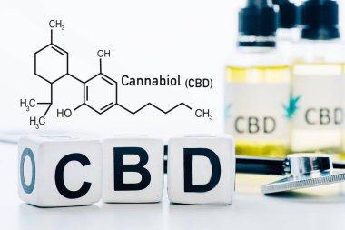 Yağ ve steteskop yanında cbd harfleri olan küplerin seçici odak noktası cbd moleküllü beyaza izole edilmiş.