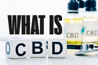 Yağ ve steteskop yakınındaki cbd harfli küplerin seçici odak noktası beyaz üzerine izole edilmiş Cbd sorusu nedir