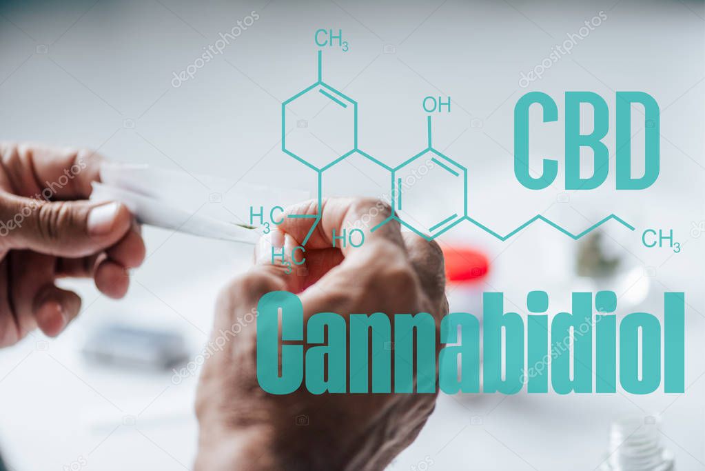 cropped view of man holding blunt of medical cannabis with cbd molecule illustration