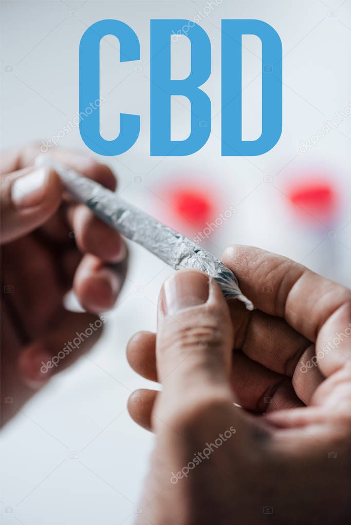 cropped view of man holding blunt of medical cannabis with CBD word