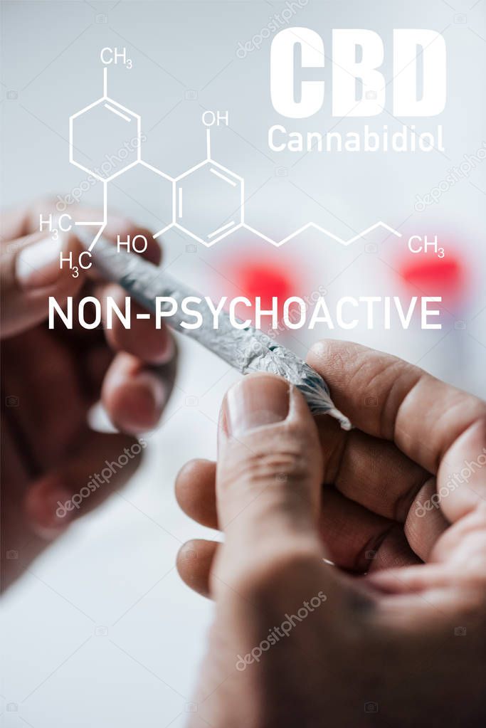 cropped view of man holding blunt of medical cannabis with non-psychoactive cbd illustration