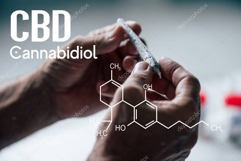 cropped view of man holding blunt of medical cannabis with cbd molecule illustration
