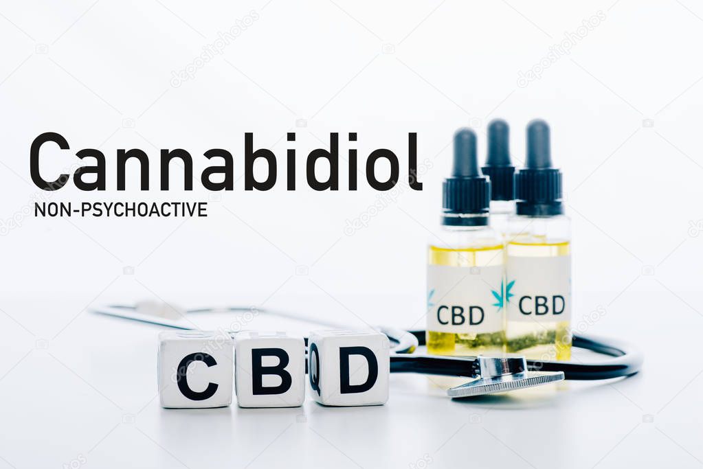 cubes with cbd lettering near oil and stethoscope isolated on white with non-psychoactive cbd illustration