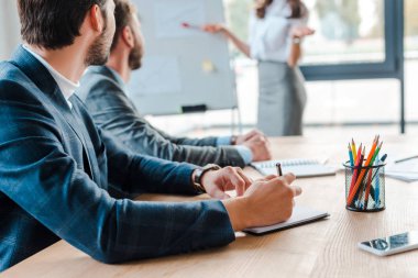 Reklam tablosunun yanında duran hoparlör ve ofiste çalışan iş adamları. 