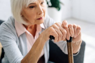 Dairesinde tahta baston olan yaşlı bir kadının seçici odağı. 