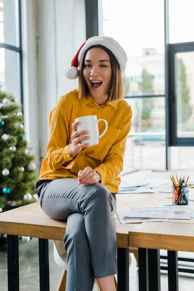 Veselá Asijská Žena Santa Klobouk Kávou Blízkosti Zdobené Vánoční Stromeček — Stock fotografie