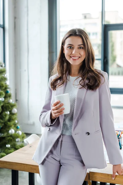 Glückliche Geschäftsfrau Hält Tasse Neben Geschmücktem Weihnachtsbaum — Stockfoto