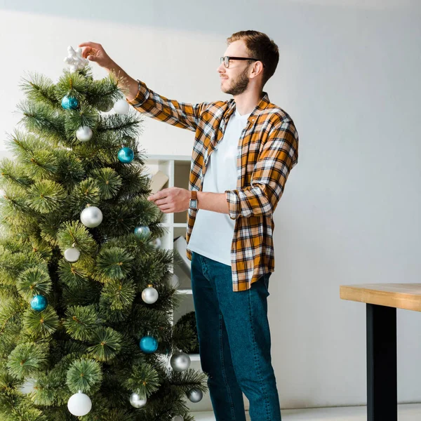 戴眼镜的英俊大胡子男人装饰着圣诞树 — 图库照片