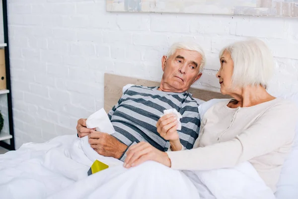 ill husband and wife holding napkins and talking in apartment