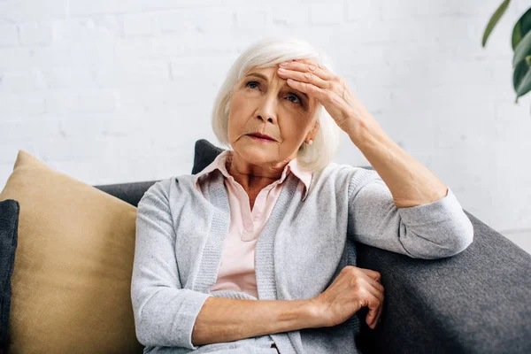 老年妇女头痛 坐在公寓沙发上 — 图库照片