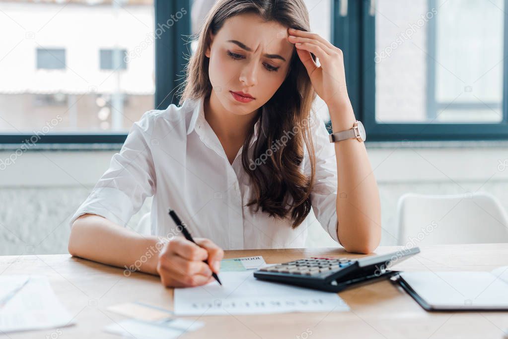 frustrated businesswoman signing document near calculator 