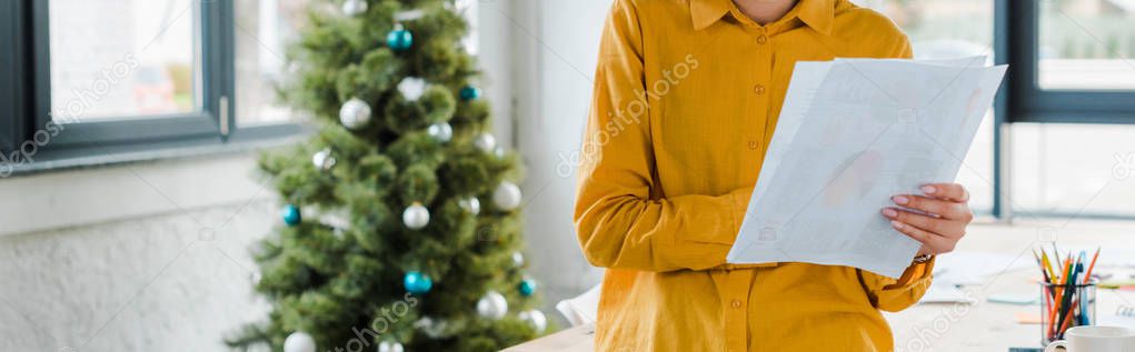 panoramic shot of woman holding paper near decorated christmas tree 