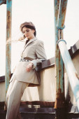 beautiful fashionable woman posing in beige suit and beret on roof