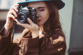 attraktive Frau mit Hut fotografiert mit Retro-Fotokamera auf dem Dach
