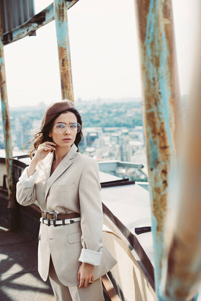 elegant stylish woman posing in beige suit and beret on roof