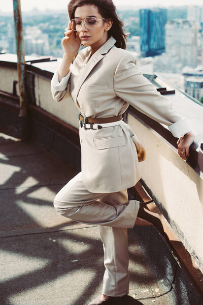 attractive stylish elegant woman posing in beige suit and beret on roof