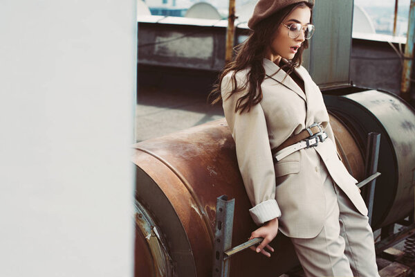 fashionable elegant model posing in beige suit and beret on roof