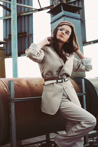 attractive stylish model posing in beige suit and beret on urban roof