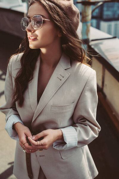 elegant stylish girl posing in beige suit and beret on urban roof