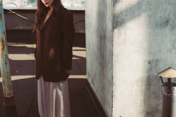 Cropped view of elegant model posing in silk dress and brown jacket on roof — Stock Image Cropped View Elegant Model Posing Silk Dress Brown Jacket Roof Royalty Free Stock Photos