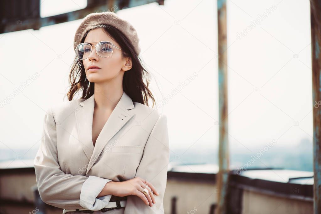 attractive elegant woman posing in beige suit and beret on roof