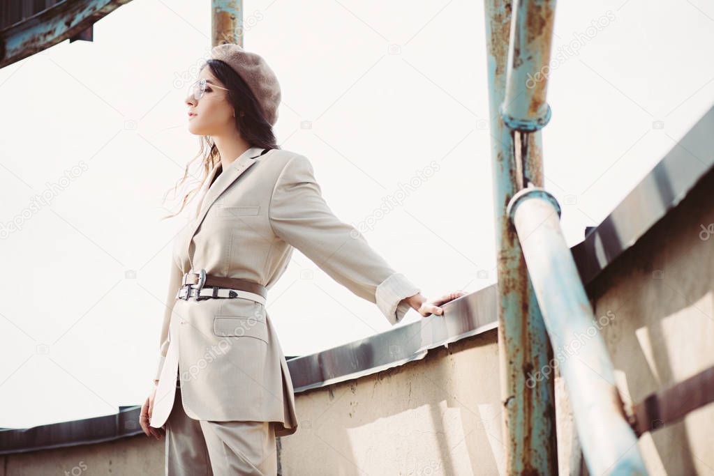 elegant fashionable woman posing in beige suit and beret on roof
