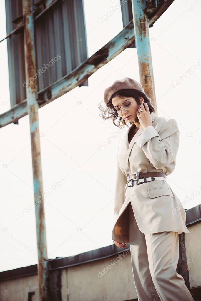 attractive stylish woman posing in beige suit and beret on roof
