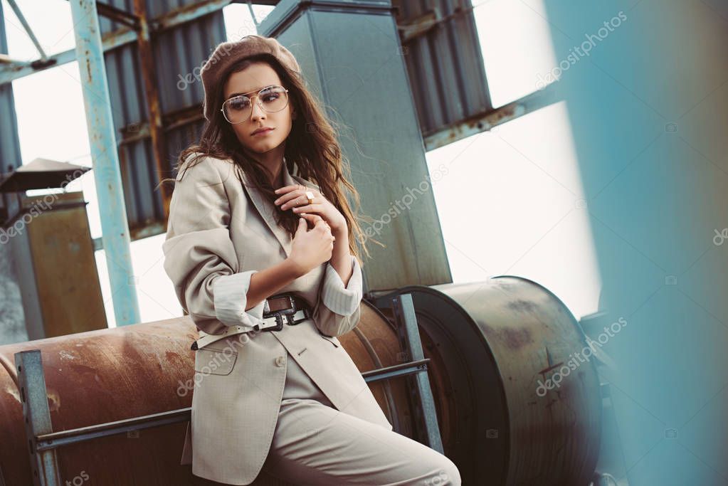 attractive fashionable model posing in beige suit and beret on urban roof