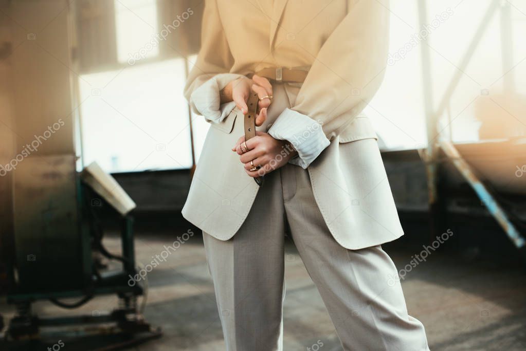 cropped view of elegant trendy woman posing in beige suit on urban roof