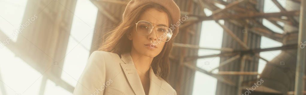 beautiful girl posing in beige suit and trendy beret on urban roof