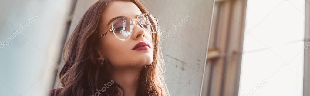 elegant girl posing in trendy burgundy suit and sunglasses on urban roof 