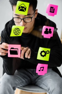 Asyalı seo yöneticisi cam üzerine resimli kağıt yapıştırıyor 