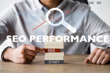 cropped view of seo manager holding rectangle with seo lettering and sitting near seo performance illustration  clipart