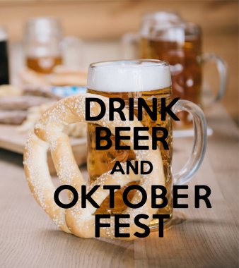 Kızarmış sosisler, soğan halkaları, patates kızartmaları, krakerler ve bardaklarda bira, bira ve Ekim Festivali resimli ahşap masa.