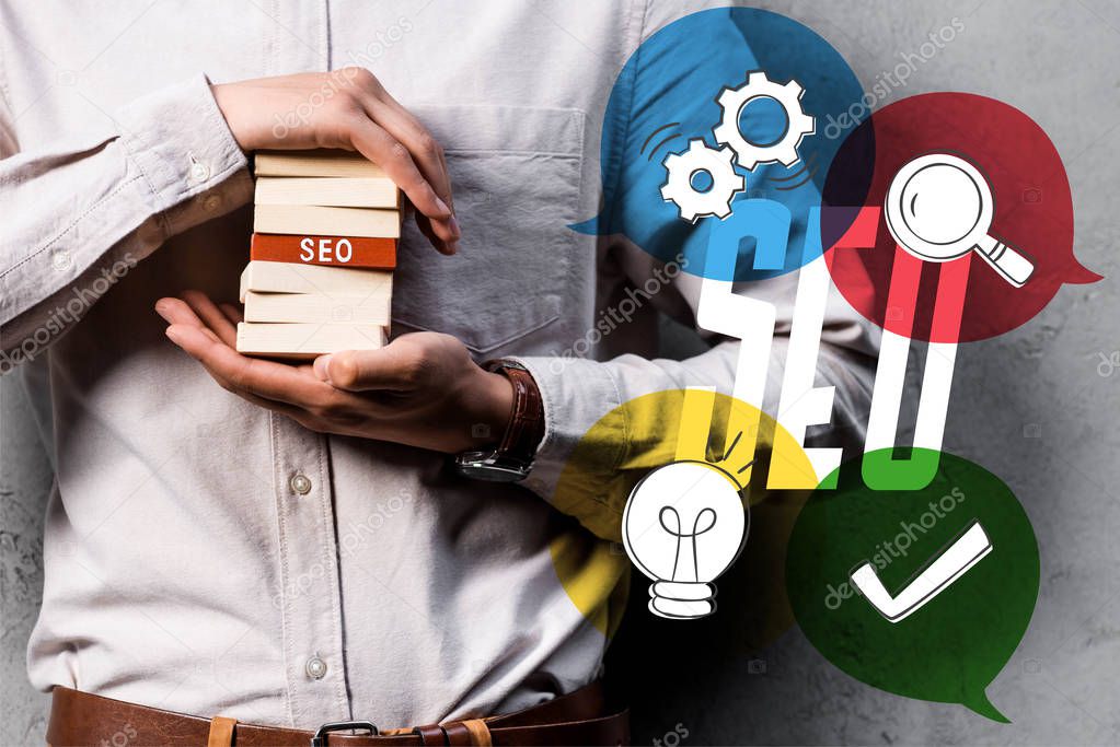 cropped view of seo manager holding wooden rectangles and standing near seo illustration