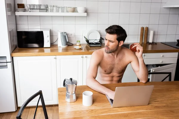 Freelancer Pensativo Comer Maçã Enquanto Trabalhava Laptop Cozinha — Fotografia de Stock